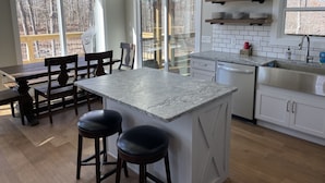 A modern kitchen with a central island, wooden chairs, and a dining table.