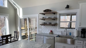A modern kitchen with white cabinets, a granite countertop, and a large window.