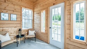 A wooden cabin interior with a bench, a chair, and a door with a number. - Stunning Ocean Front cottage, minutes from the beach (bayswater)