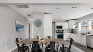 A modern kitchen with white cabinets, a wooden dining table, and black chairs. - Your Dynamic Retreat | Park Circle Paradise (North Charleston)