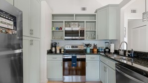 Een moderne keuken met roestvrijstalen apparatuur, lichte kasten en een granieten aanrecht.