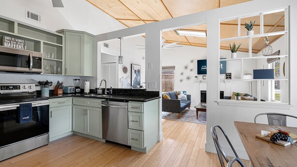 Een moderne keuken met een centraal eiland, inbouwapparatuur en een eethoek met een houten tafel en stoelen.
