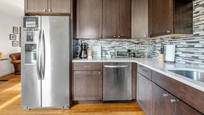 A modern kitchen with dark wooden cabinets, stainless steel appliances, and a tiled backsplash. - 5 Minute Drive To The Beach! Old Village Getaway (Mount Pleasant)