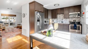 A modern kitchen with dark wood cabinets, stainless steel appliances, and a marble countertop. - 5 Minute Drive To The Beach! Old Village Getaway (Mount Pleasant)