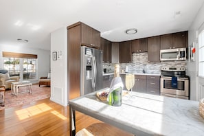 A modern kitchen with dark wood cabinets, stainless steel appliances, and a marble countertop.
