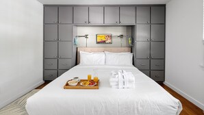 A neatly made bed with white linens, a tray with breakfast items, and a grey wardrobe with multiple drawers. - 5 Minute Drive To The Beach! Old Village Getaway (Mount Pleasant)