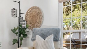 A beige leather armchair with a patterned rug, a floor lamp, and a large woven wall hanging. - 5 Minute Drive To The Beach! Old Village Getaway (Mount Pleasant)