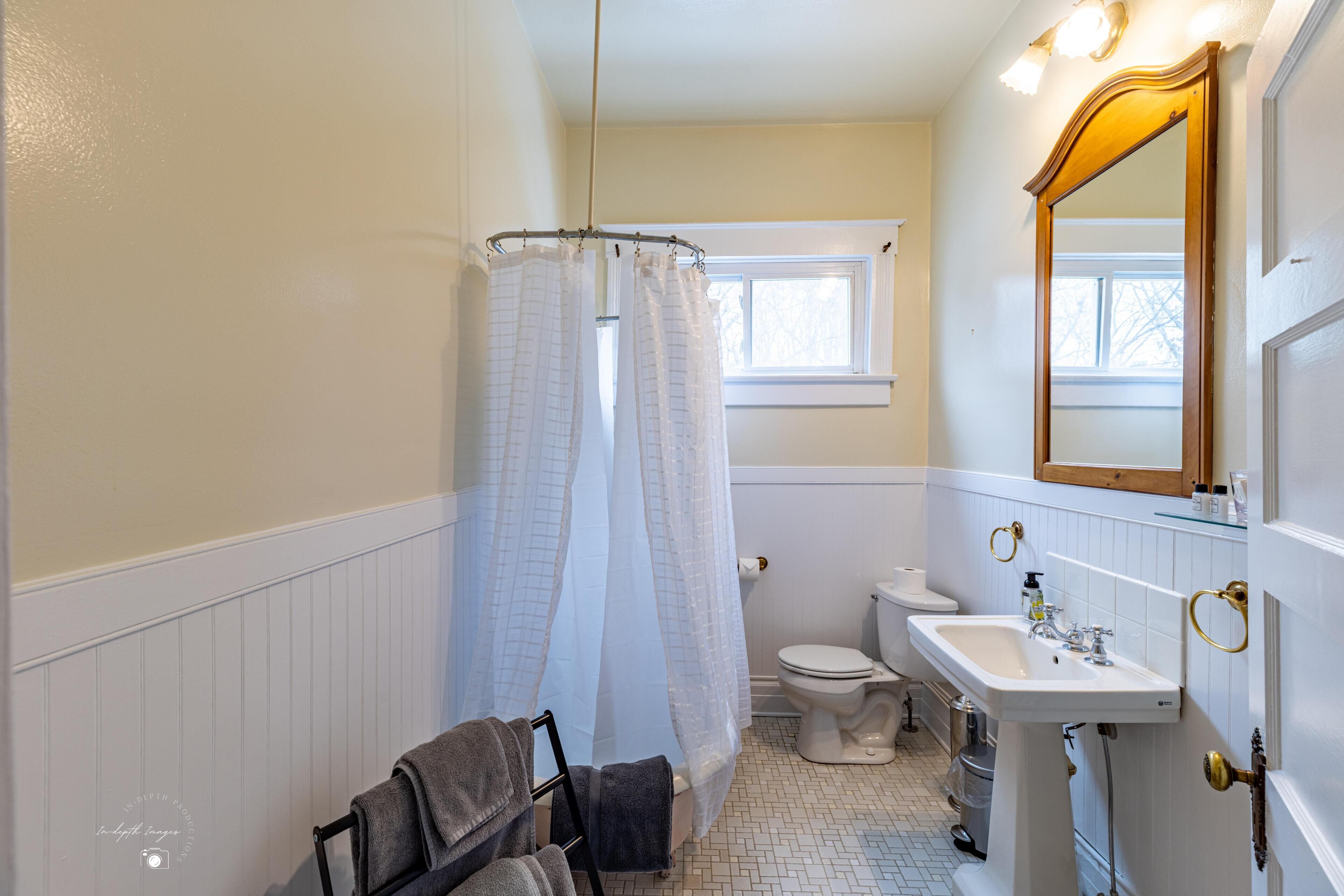 Un baño con inodoro, lavamanos y cortina de ducha.