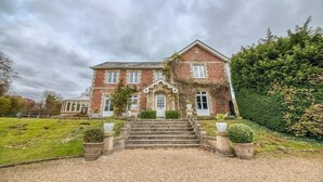 A large brick house with a symmetrical facade, a central entrance with steps, and a well-maintained lawn.