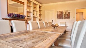 A dining area with a wooden table and white upholstered chairs.