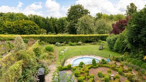 Un jardin aménagé avec une piscine, entouré de différents arbres et arbustes.