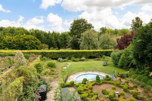 Un jardin aménagé avec une piscine, entouré de différents arbres et arbustes.