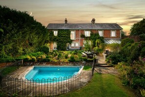 Ein Wohnhaus mit Pool, einem gepflegten Garten und einem Ziegelspeicherhaus mit Satteldach.