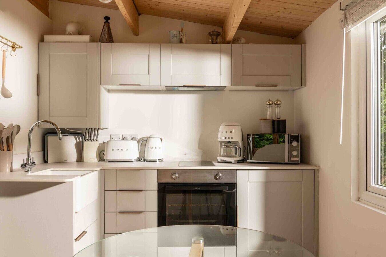 A modern kitchen with white cabinetry, a built-in oven, a coffee maker, and a microwave.