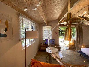 Une pièce avec un plafond en bois, une table ronde, un lit et un téléviseur.