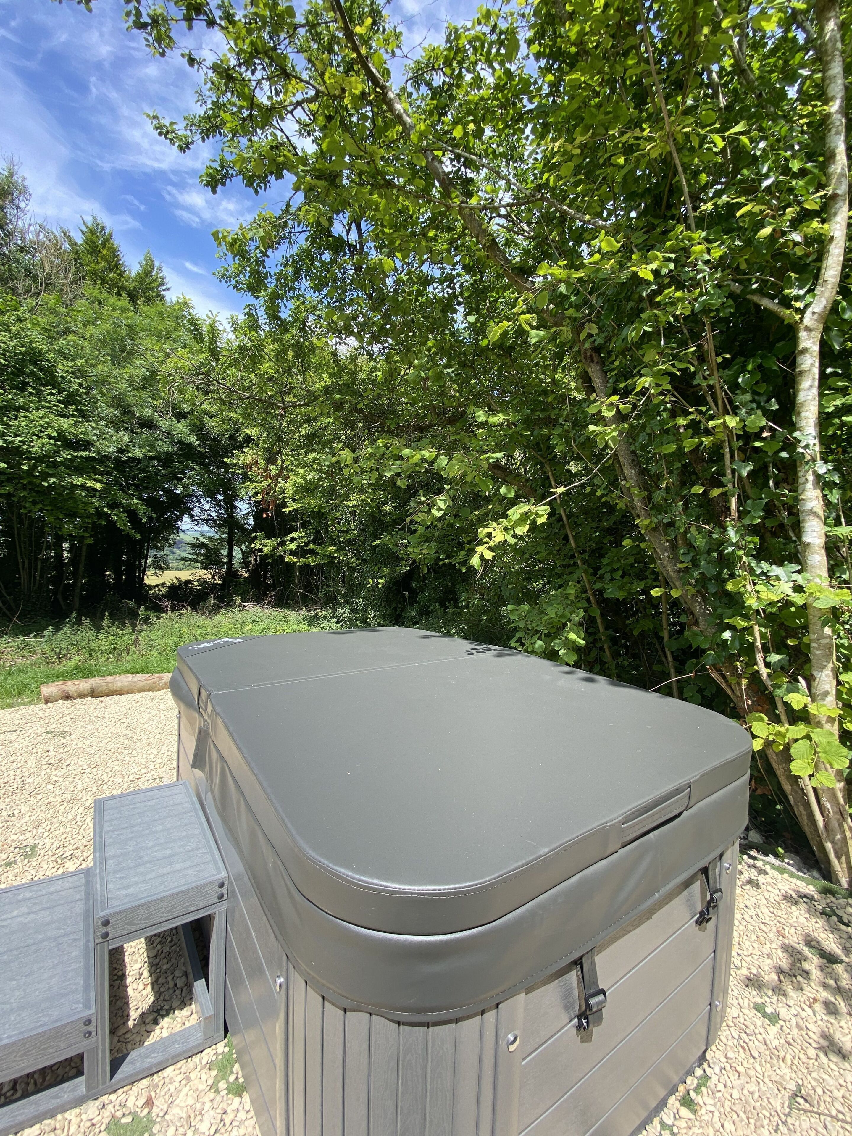 A hot tub with a wooden bench in a natural setting.