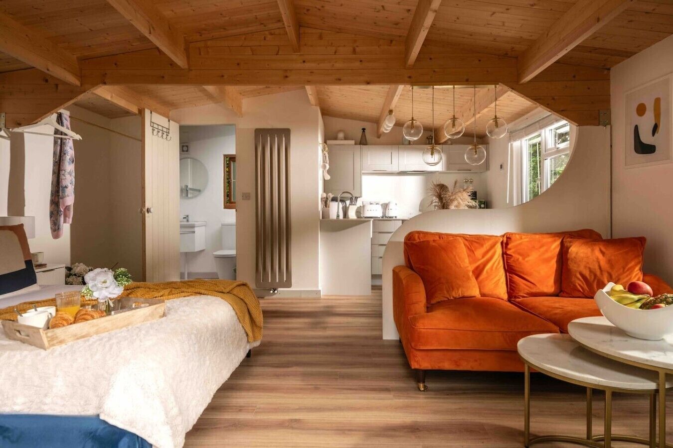 Ein gemütliches Interieur mit einem Bett, einem orangefarbenen Sofa und einem Essbereich mit einem Tisch.