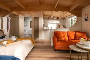 Un intérieur chaleureux avec un lit, un canapé orange et un coin repas doté d’une table.