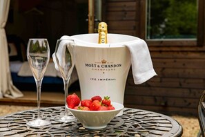 Une bouteille de champagne Moët & Chandon Ice Imperial, accompagnée d’une paille, d’un verre et d’un bol de fraises, posée sur une table.