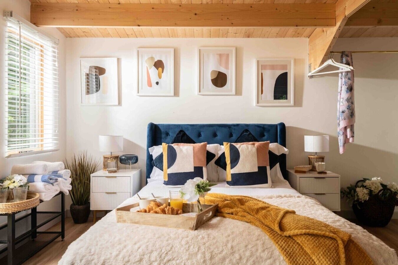 Een slaapkamer met een bed, nachtkastjes, een ontbijtplateau en kunst aan de muur.