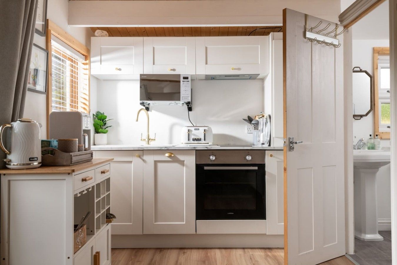 A modern kitchen with white cabinetry, a built-in oven, a microwave, and a coffee maker.