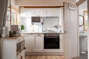 A modern kitchen with white cabinetry, a built-in oven, a microwave, and a coffee maker.