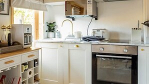 Une cuisine compacte avec des meubles blancs, un four encastré et un plafond en bois.