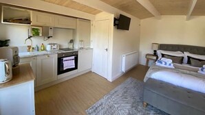 Une chambre à coucher de taille réduite, comprenant un lit, des tables de chevet et un téléviseur fixé au mur.