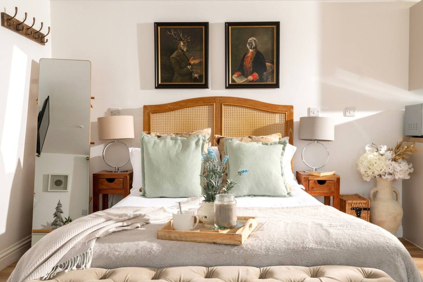 Une chambre à coucher avec un grand lit, deux tables de chevet, une tête de lit en bois et deux tableaux encadrés au-dessus du lit.
