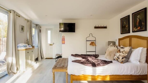 A bedroom with a bed, a TV, and a window with curtains.