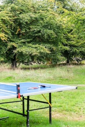 A ping pong table in an outdoor setting with a grassy area and trees in the background.