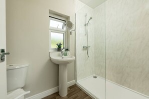 Une salle de bain comprenant des toilettes, un lavabo, une fenêtre et un espace douche.