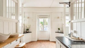 A narrow kitchen with white cabinetry, a wooden countertop, and a view through an open door to the outside. - Historic Stable on a Private Vineyard (Blandford Forum)