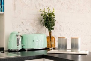 Una encimera de cocina con un tostador de estilo vintage, un florero con una planta y dos recipientes.