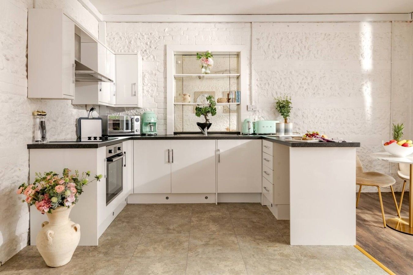 A modern kitchen with white cabinets, a central island, and a dining area with a white table and chairs.