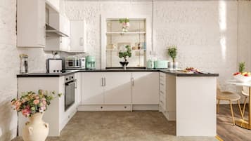 A modern kitchen with white cabinets, a central island, and a dining area with a white table and chairs.