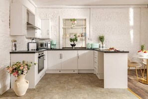 A modern kitchen with white cabinets, a central island, and a dining area with a white table and chairs.