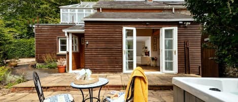 Ett trähus med en uteplats, ett bubbelbad och ett bord med stolar.