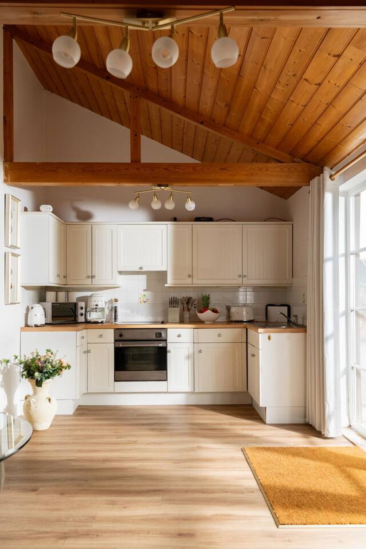 A kitchen with white cabinets, a wooden ceiling, and a built-in oven.