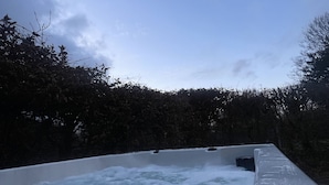 Un bain à remous entouré de neige et d’arbres.
