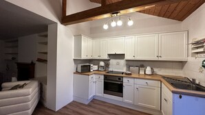 Une cuisine de taille réduite avec des meubles blancs, un four à micro-ondes, un grille-pain et un évier.