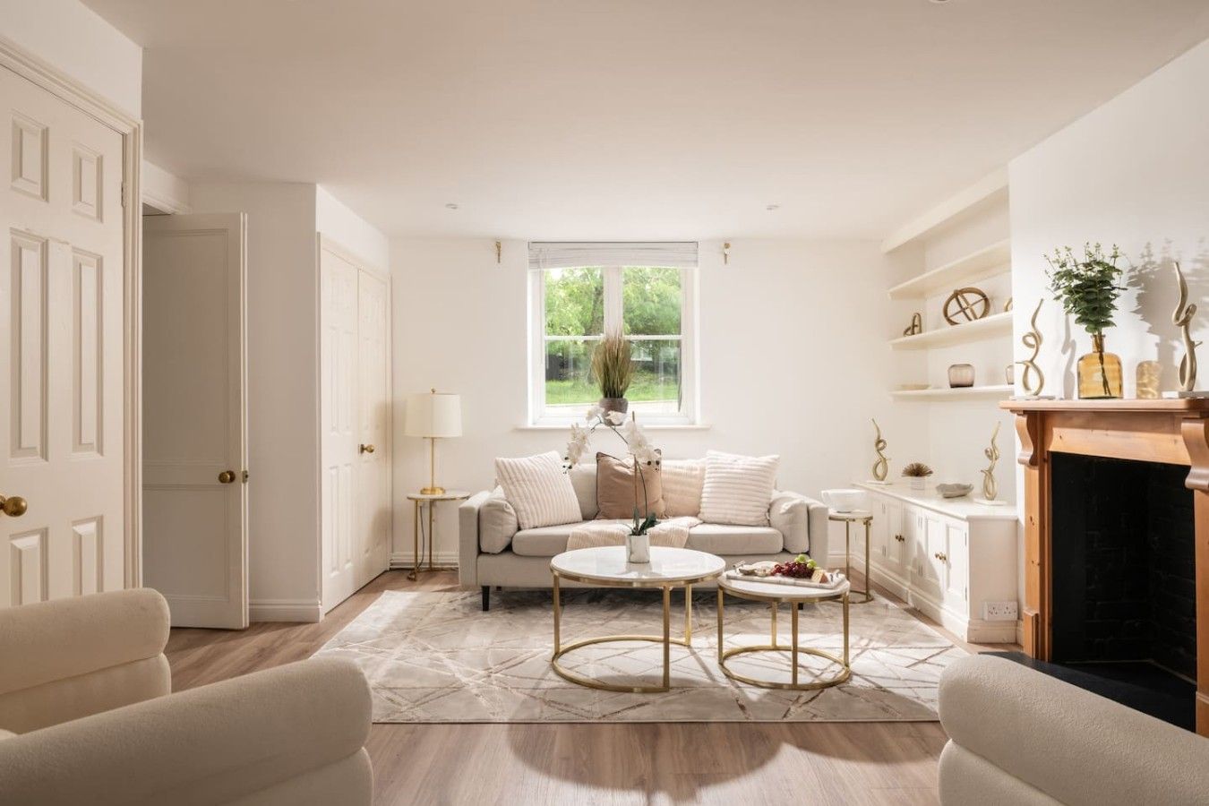 A living room with a sofa, two coffee tables, a fireplace, and a window with a view of greenery.