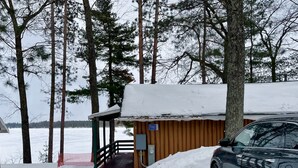 Una cabaña con fachada de madera, un porche cubierto y un techo cubierto de nieve.