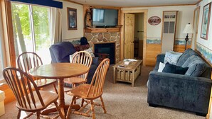 Una sala acogedora con chimenea, televisor y comedor con mobiliario de madera.
