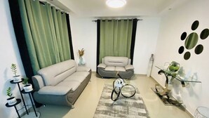 A modern living room with a beige sofa, a grey armchair, a small table with a vase, and a bicycle.