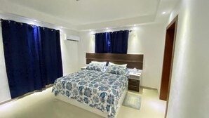 A modern bedroom with a large bed, a wooden headboard, and a nightstand.