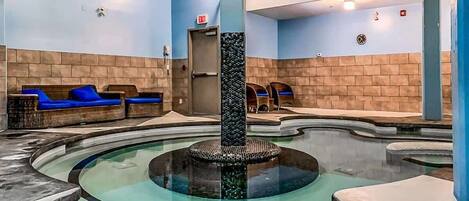 A spa area with a central fountain, seating areas, and a brick wall.