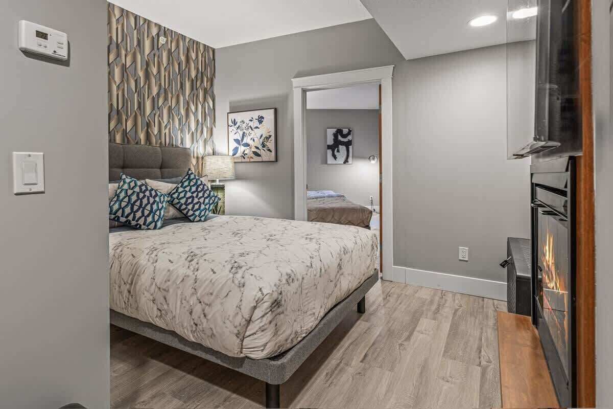 Une chambre à coucher moderne avec un lit, une cheminée et un thermostat fixé au mur.