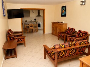 A living room with a sofa set, a wooden coffee table, and a TV mounted on the wall.