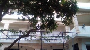 A building with a balcony, a tree in front, and a clear view of the street. - 4-bedroom apartment near the beaches and attractions • Gated and secure residential community • The Beleric (Dakar)